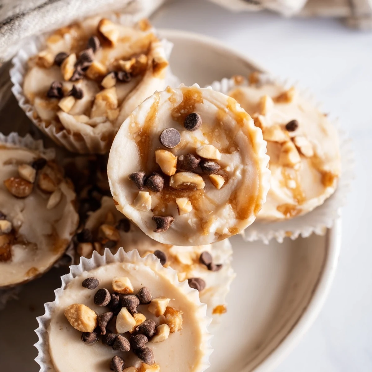 Stack of protein-packed frozen peanut butter Greek yogurt bites topped with coconut flakes in a muffin tin