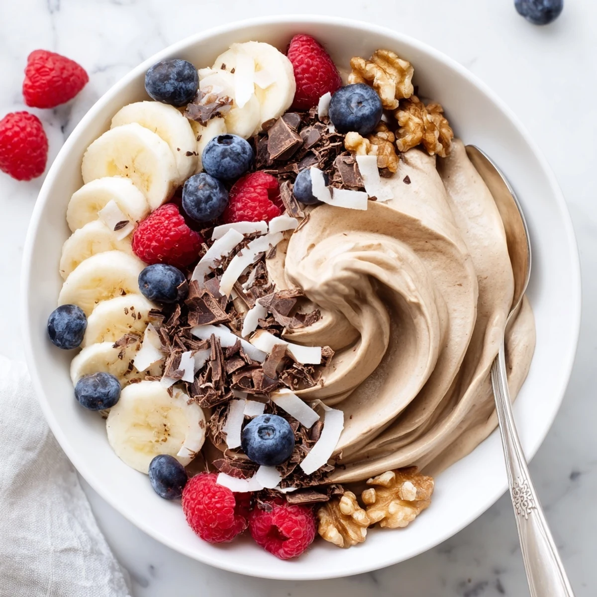 Creamy healthy nice cream recipe topped with fresh berries and dark chocolate shavings in a bowl