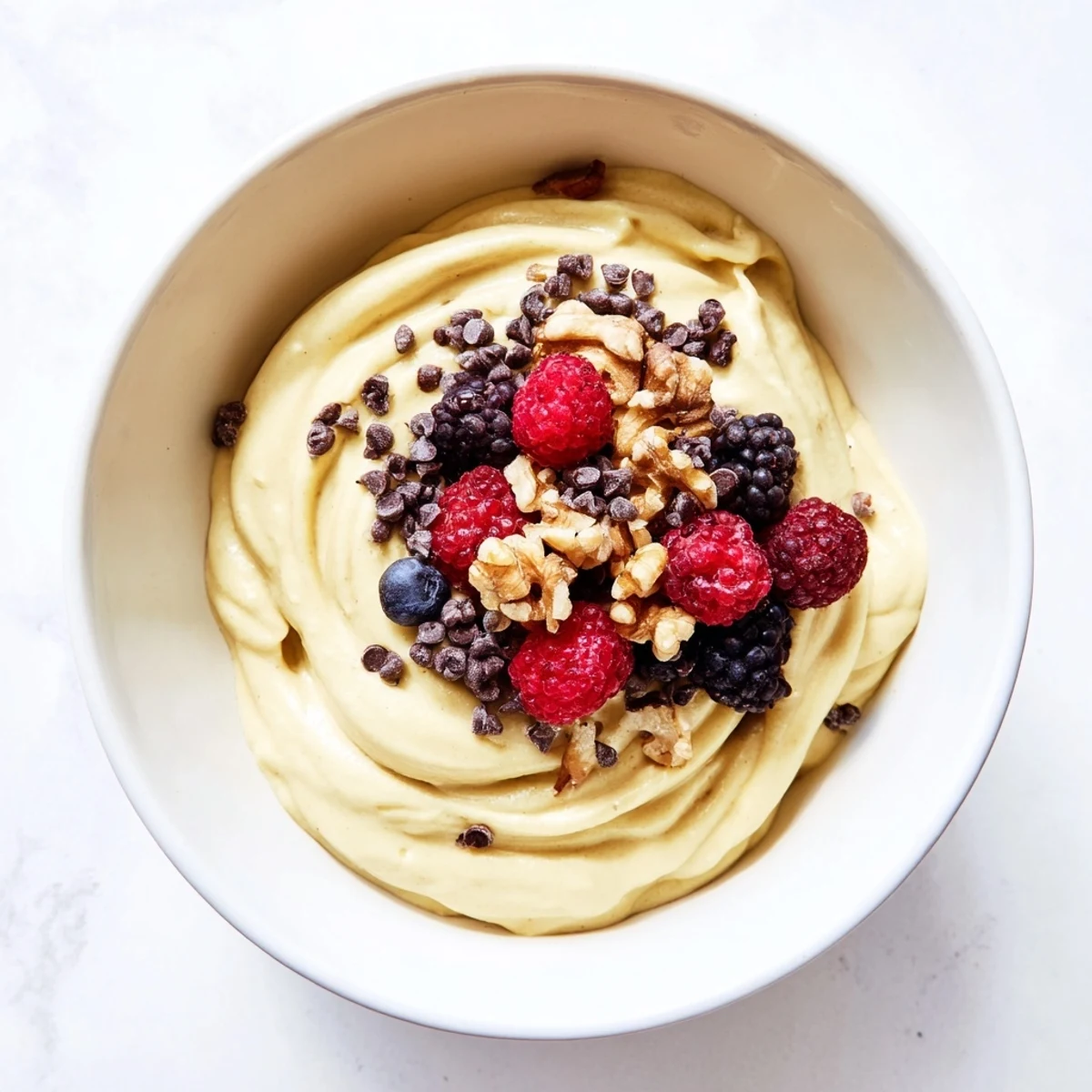 Vibrant banana nice cream with smooth soft serve texture garnished with dark chocolate shavings and coconut flakes