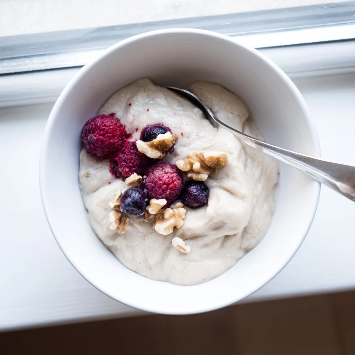 Dairy-free banana nice cream with smooth soft-serve texture scooped into a decorative glass
