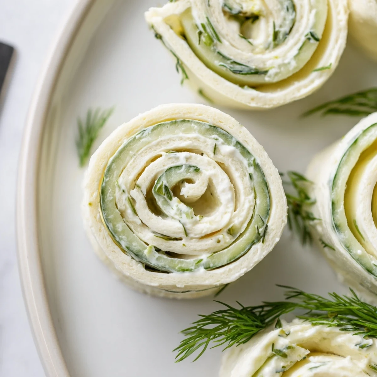 Cucumber And Dill Pinwheels on platter, creamy filling and crisp cucumber bites