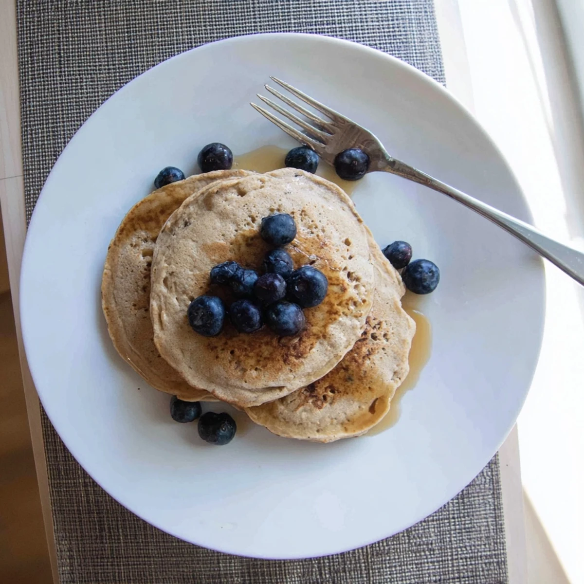 Golden stack of protein banana pancakes drizzled with maple syrup and fresh berries