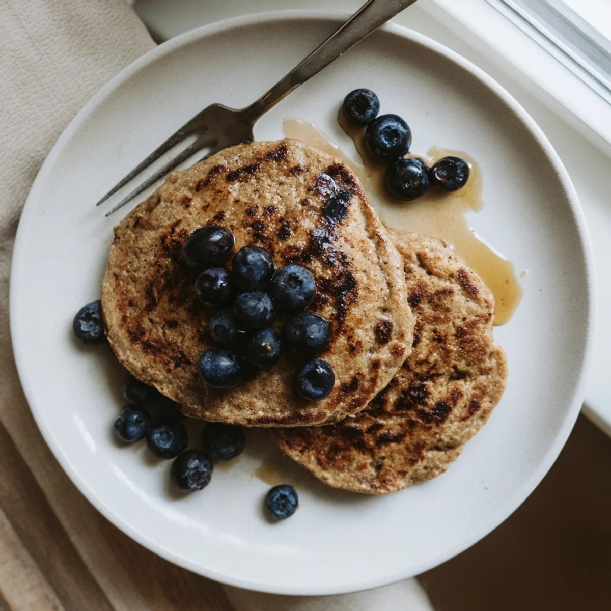 Healthy breakfast plate featuring fluffy protein banana pancakes topped with sliced banana