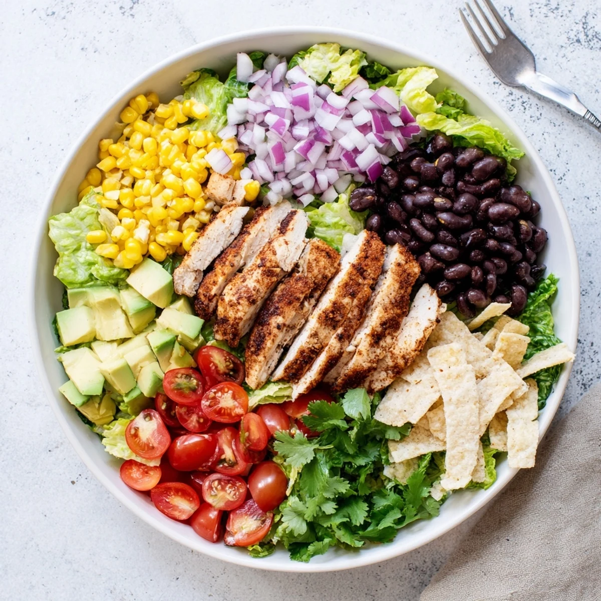 Colorful Southwestern chicken salad bowl with grilled chicken slices, black beans, corn, avocado, and creamy lime drizzle
