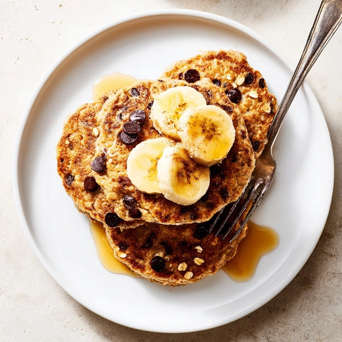 Golden brown protein banana pancakes stacked high with fresh sliced banana topping