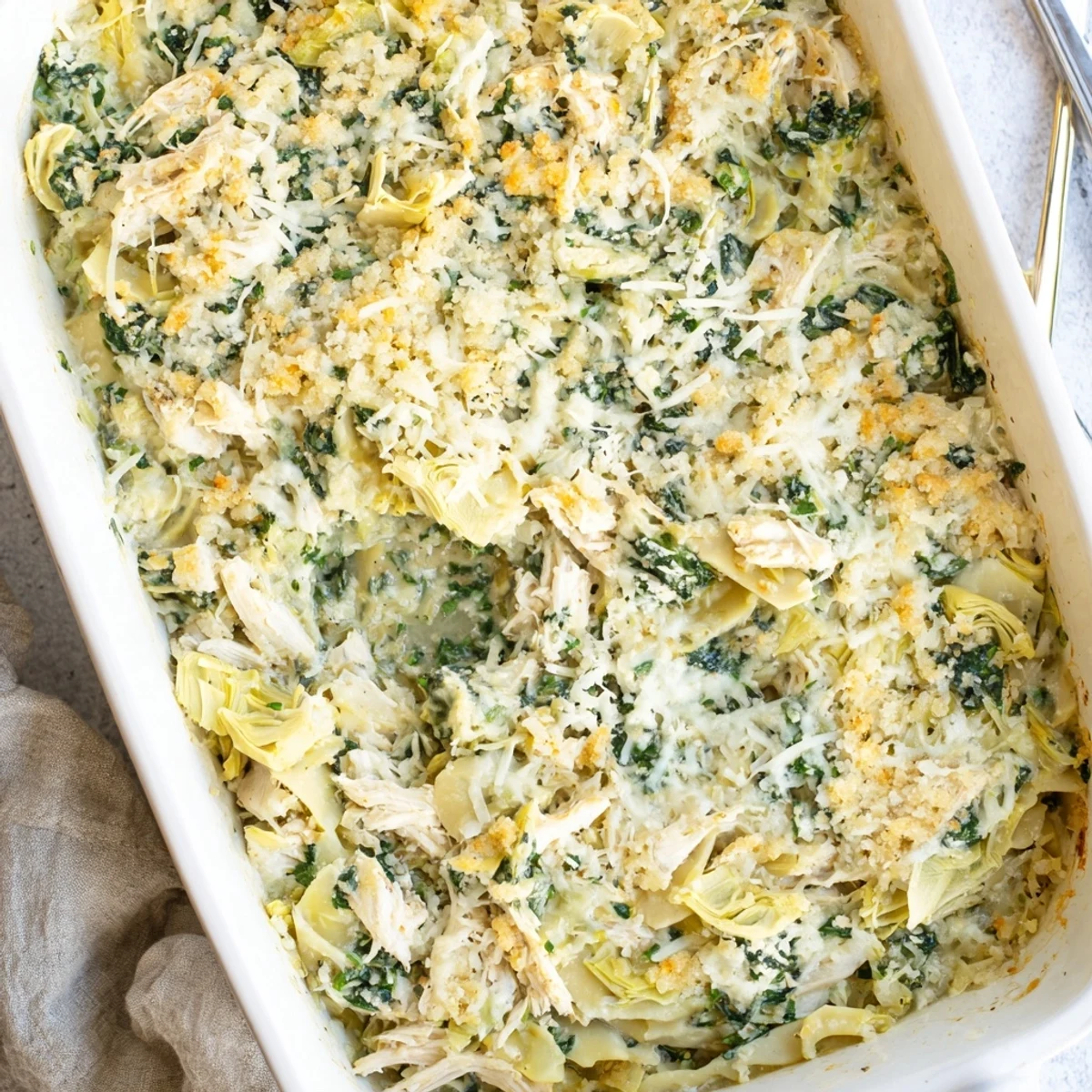 Golden baked spinach artichoke chicken casserole with bubbly melted cheese and crispy breadcrumb topping