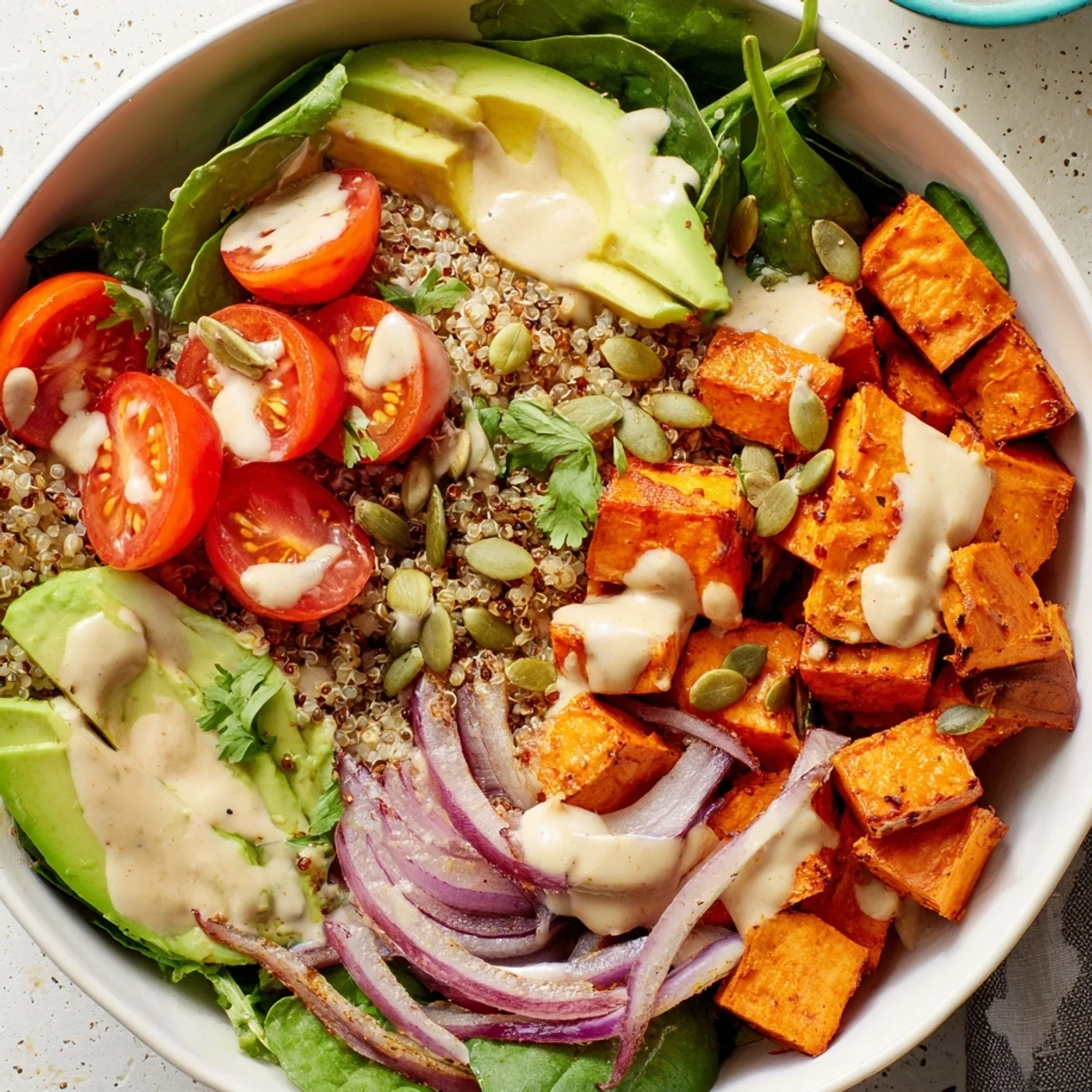 Warm sweet potato bowl topped with cherry tomatoes, avocado, and zesty tahini