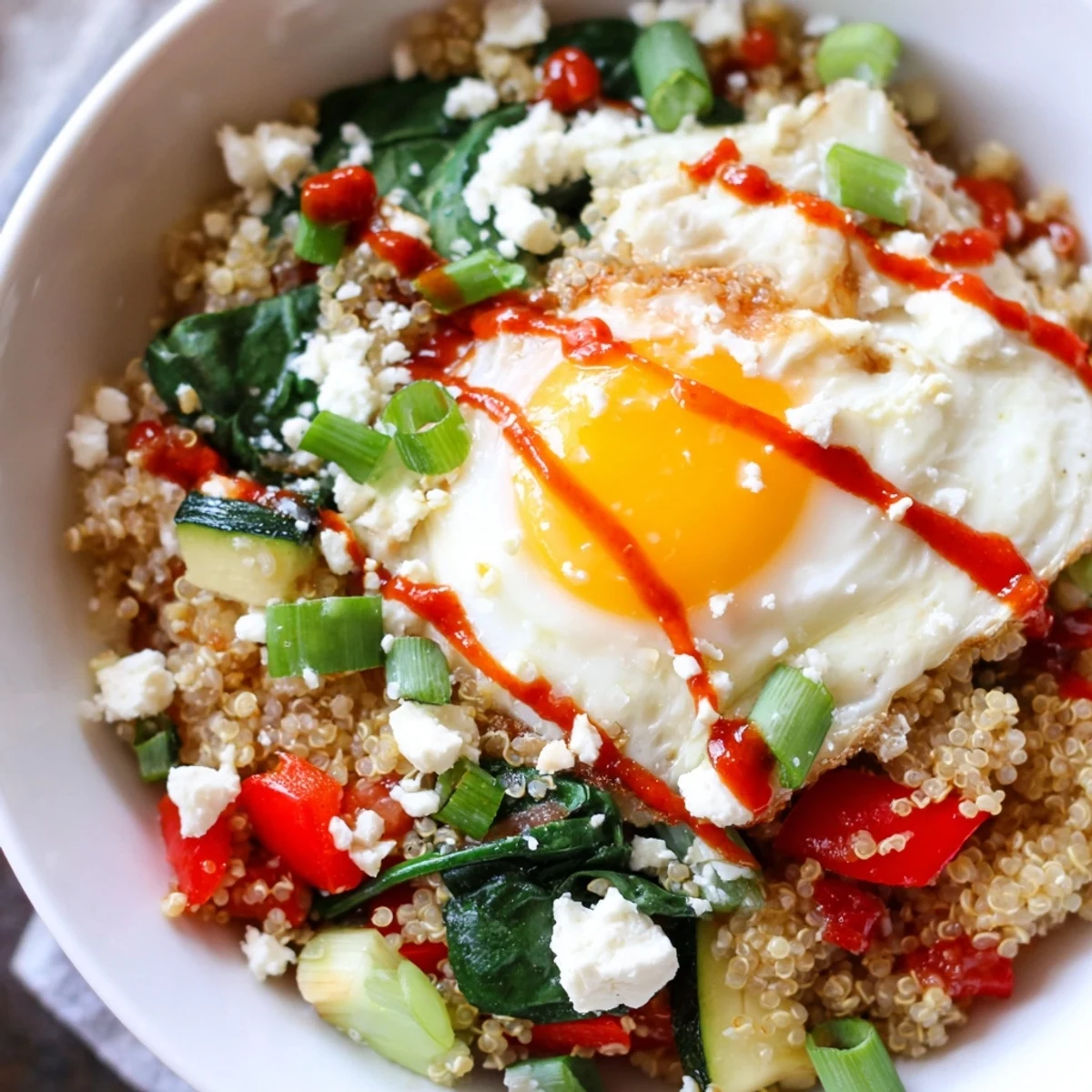 Golden savory quinoa breakfast bowl topped with a runny egg and fresh herbs
