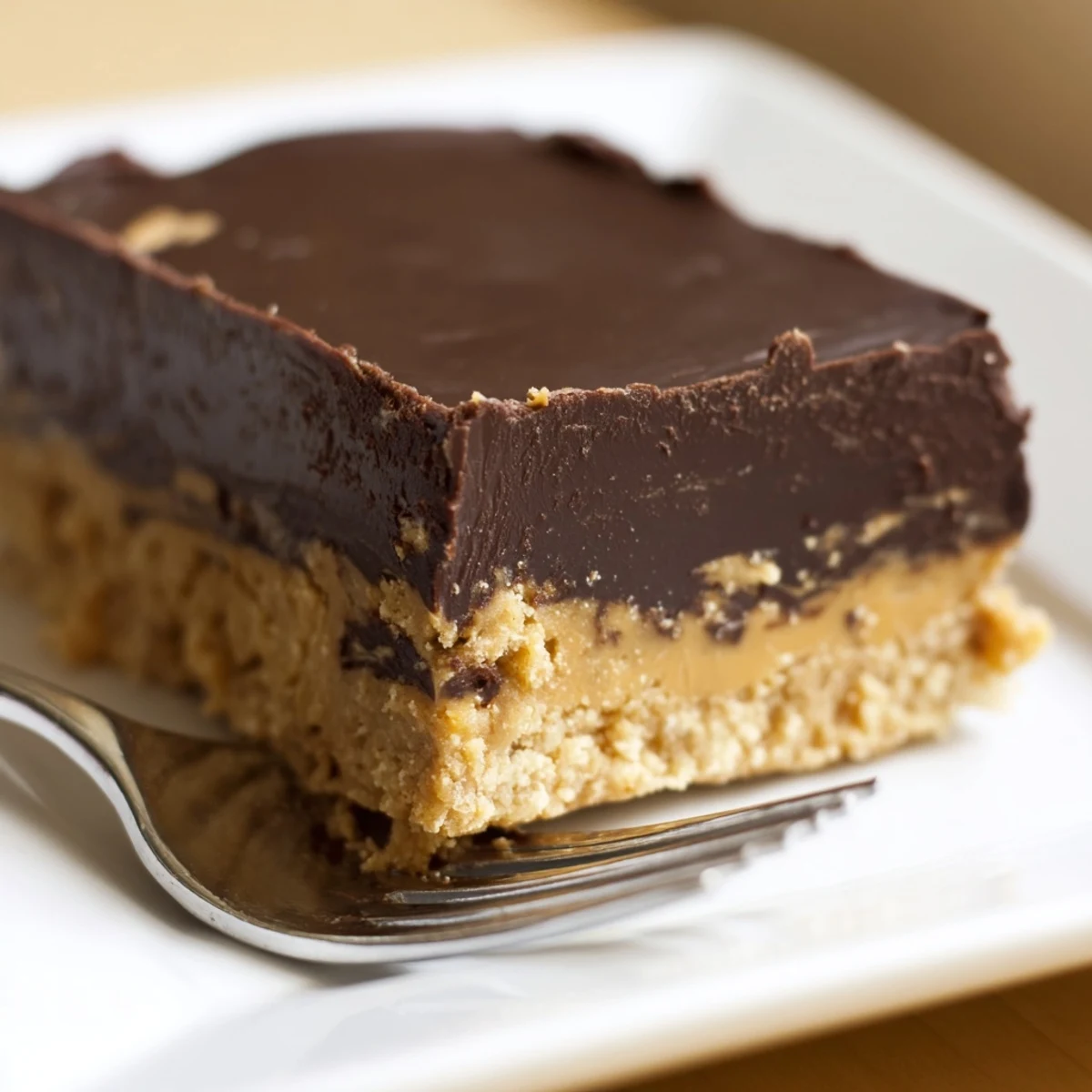 No-bake peanut butter bars topped with smooth dark chocolate and served on a white plate