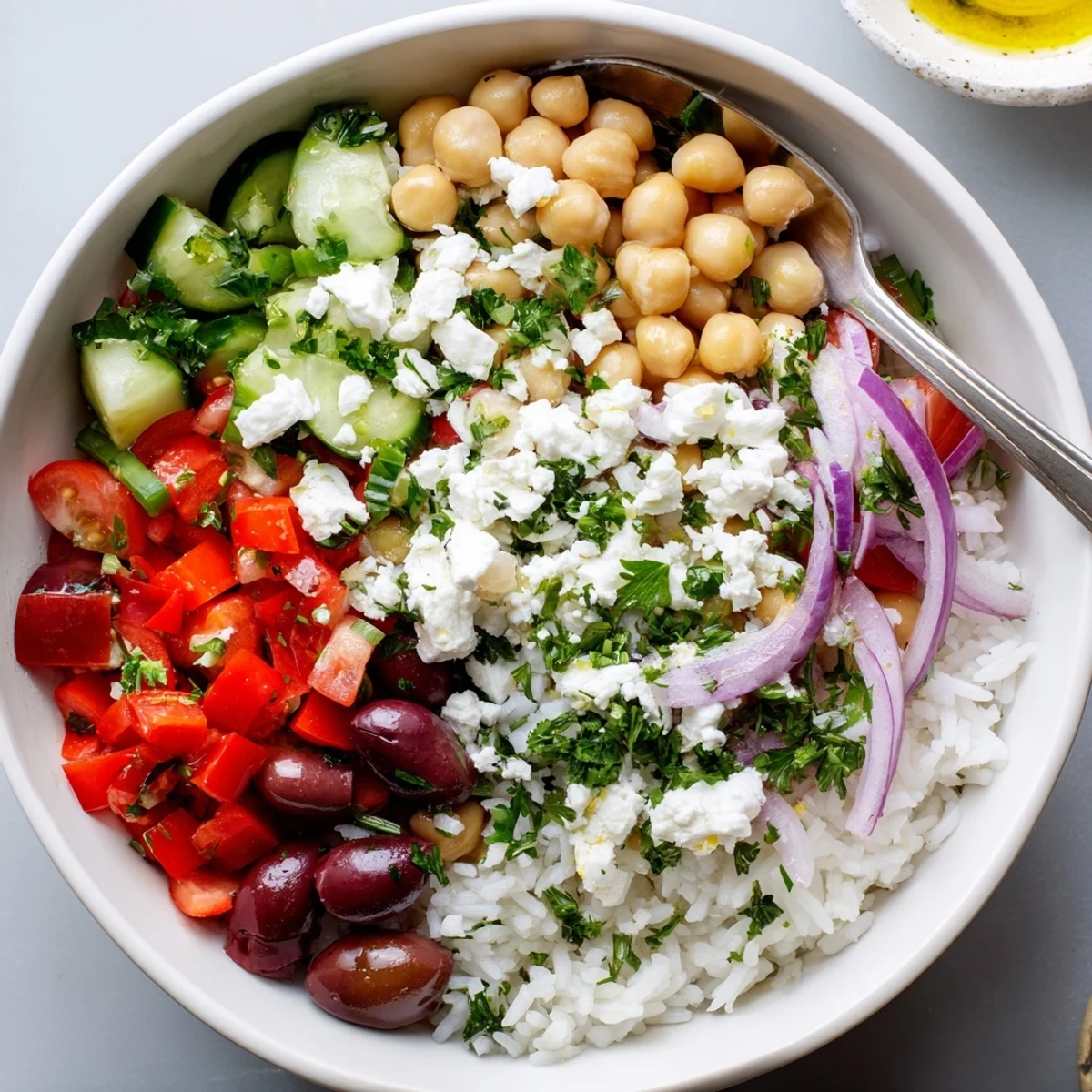 Fresh Mediterranean rice bowl drizzled with lemon herb dressing over vibrant chopped vegetables