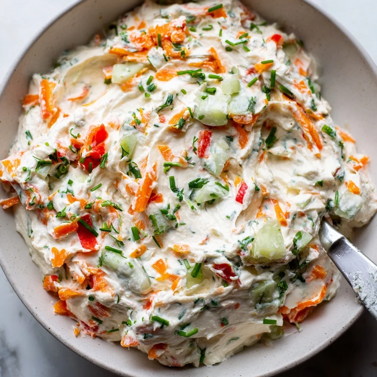 Creamy garden vegetable spread topped with fresh herbs served alongside crispy crackers
