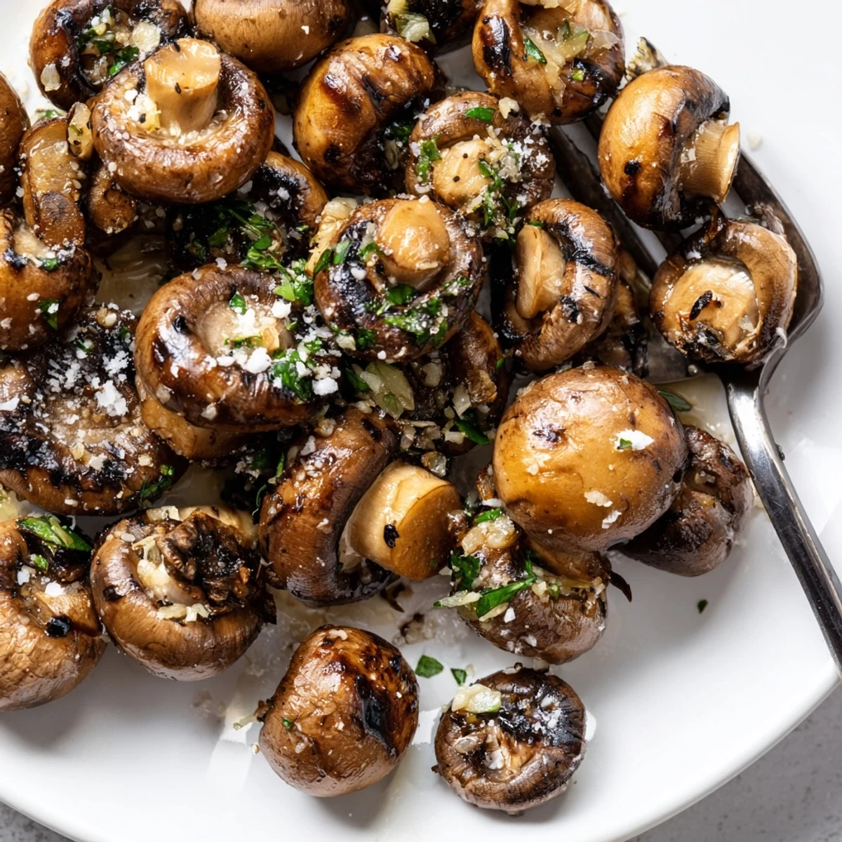 Golden sautéed grilled garlic mushrooms glistening with olive oil and fresh herbs