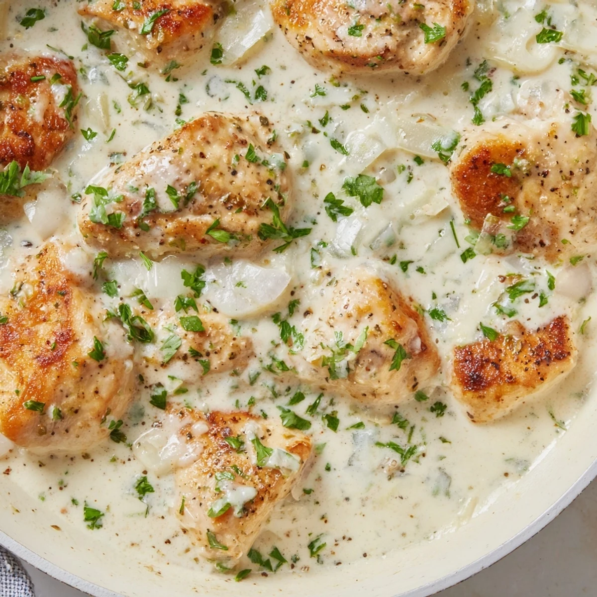 Cream Cheese Chicken served in a golden skillet with bubbling Parmesan sauce