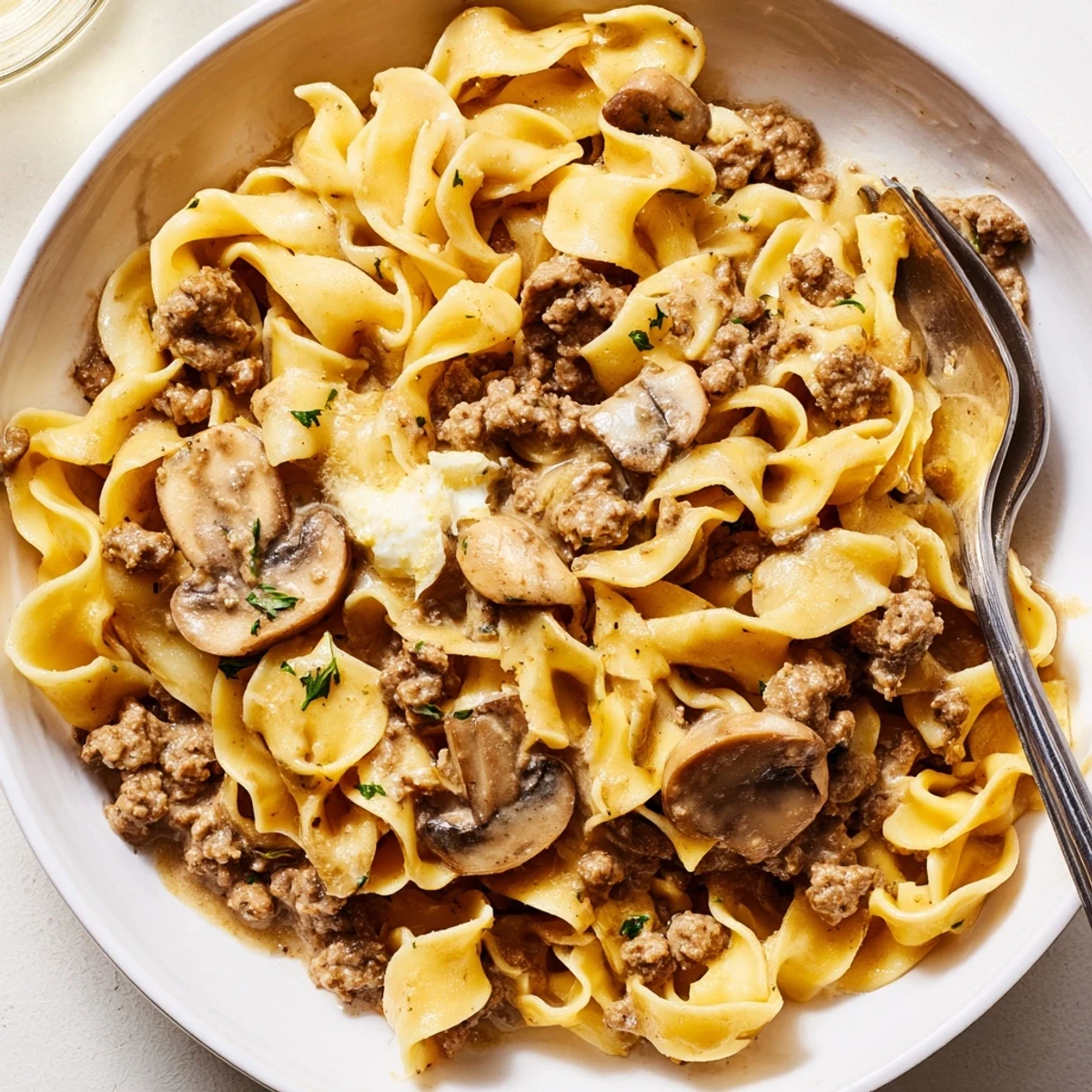 Creamy hamburger stroganoff served over tender egg noodles with fresh parsley garnish