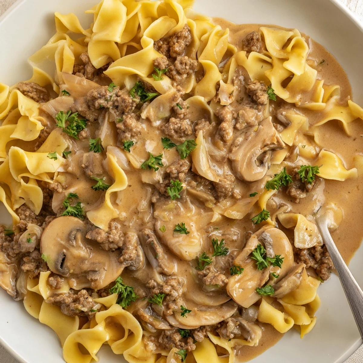 Steaming bowl of hamburger stroganoff featuring golden browned beef and creamy mushroom sauce