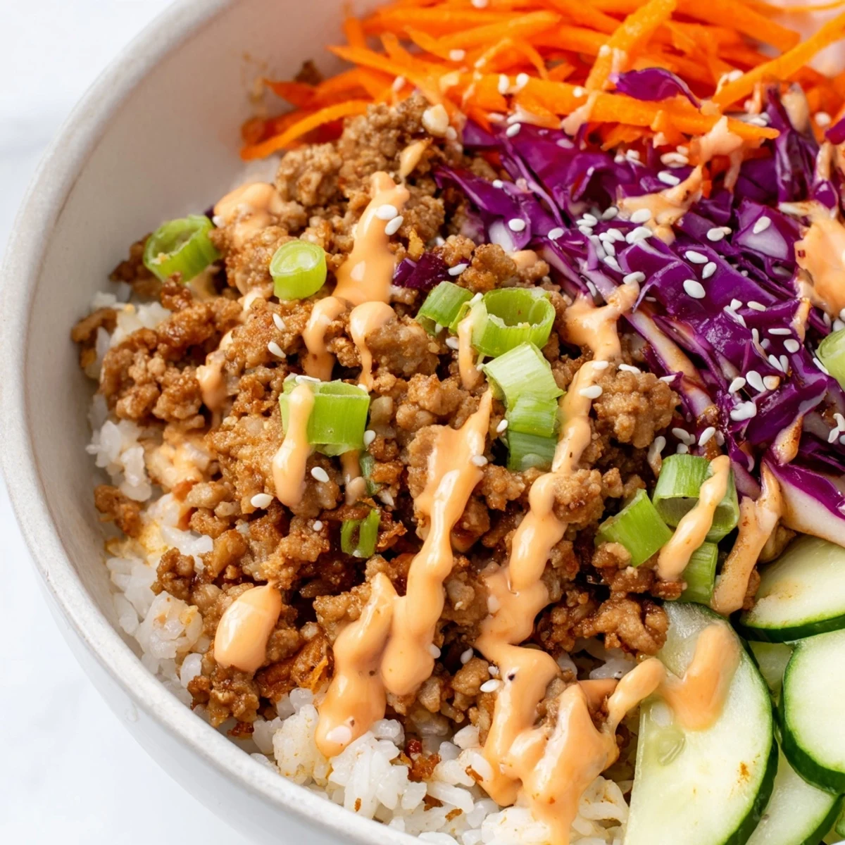 Steaming bowls of fluffy rice loaded with savory Ground Turkey Rice Bowls and spicy sauce