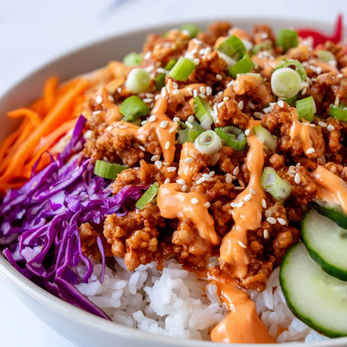 Ground Turkey Rice Bowls garnished with sesame seeds, shredded carrots, and creamy Bang Bang drizzle