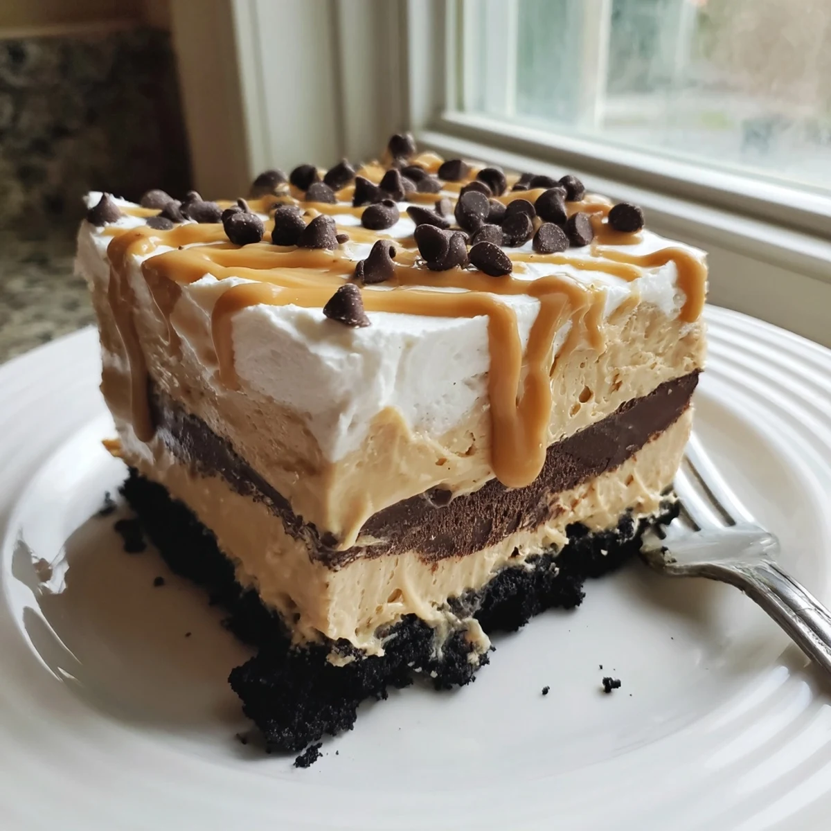 Peanut butter layered delight sliced into neat squares showing cookie crust and fluffy whipped topping
