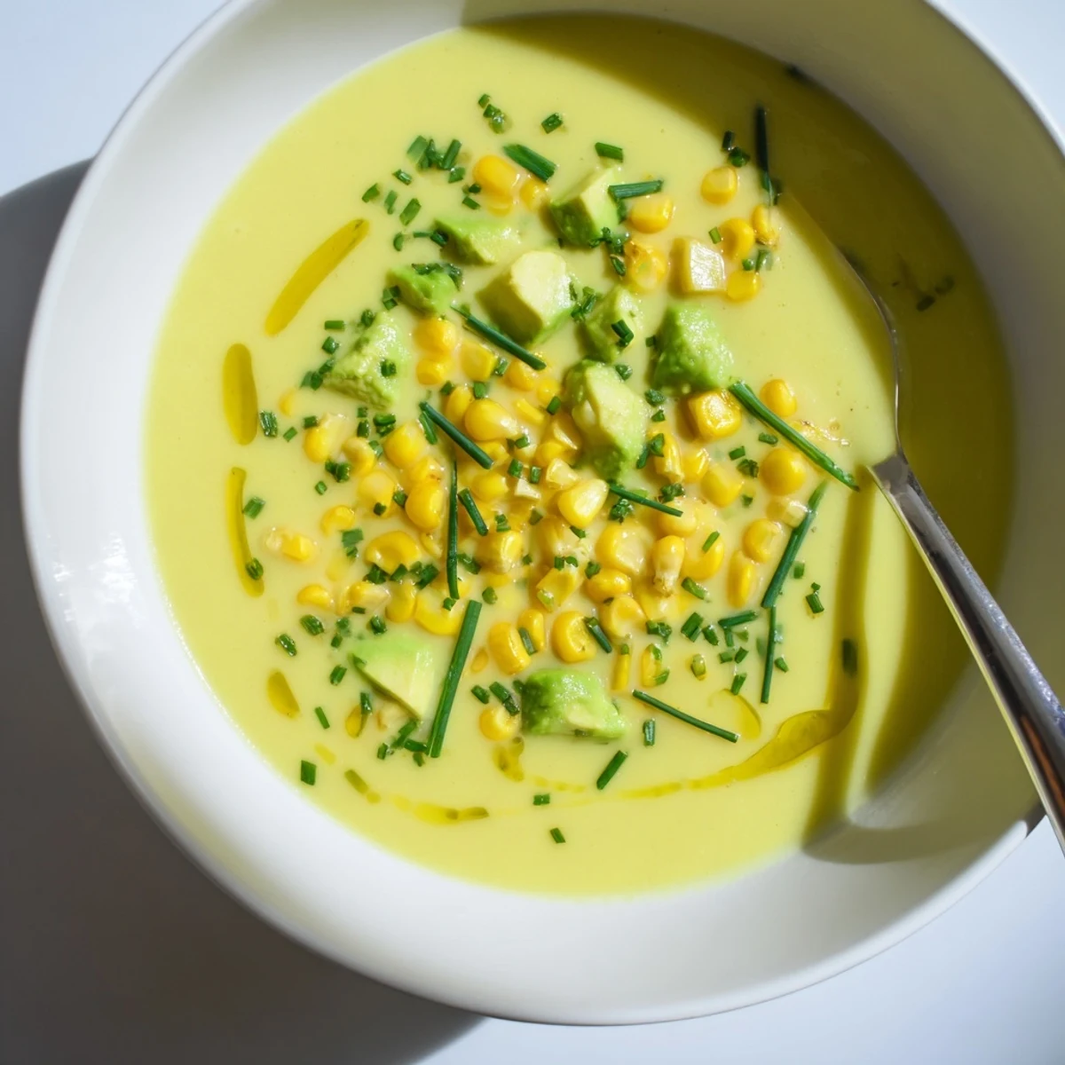 Golden Summer Sweet Corn Gazpacho served chilled in a bowl with avocado garnish