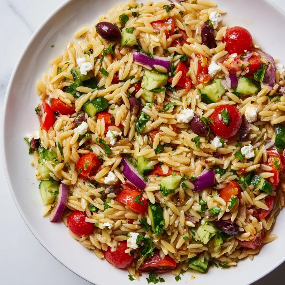 Juicy Mediterranean Orzo Pasta Salad nestled in a bright white bowl with fresh herbs on a rustic wooden table, glistening with lemon olive oil dressing