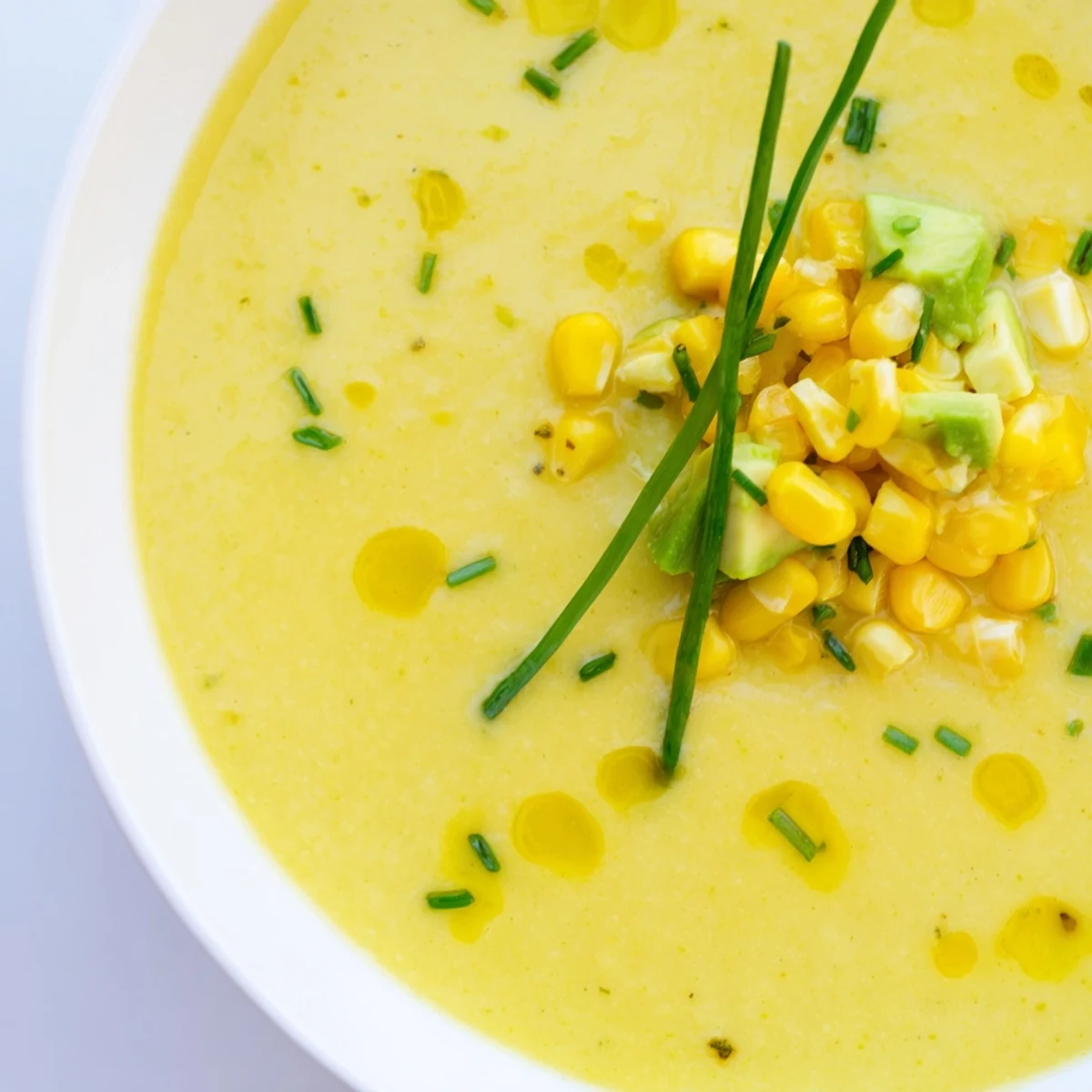 Creamy summer sweet corn gazpacho topped with diced avocado and a drizzle of olive oil