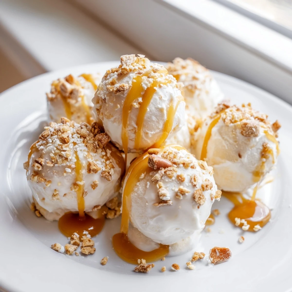 Crunchy pretzel-coated salted caramel cheesecake balls garnished with flaky sea salt and sweet caramel