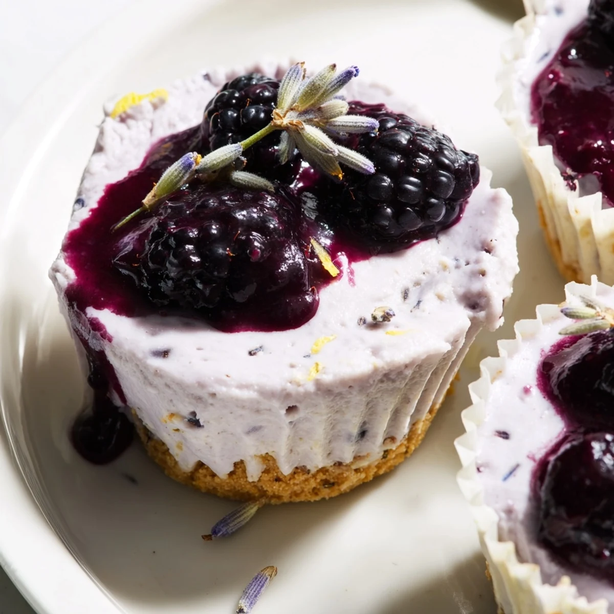 Silky no bake mini blackberry lavender cheesecakes in paper liners with fresh blackberry garnish