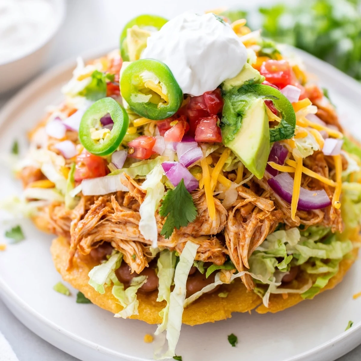 Vibrant chicken tostadas served with lettuce, avocado, and a lime wedge