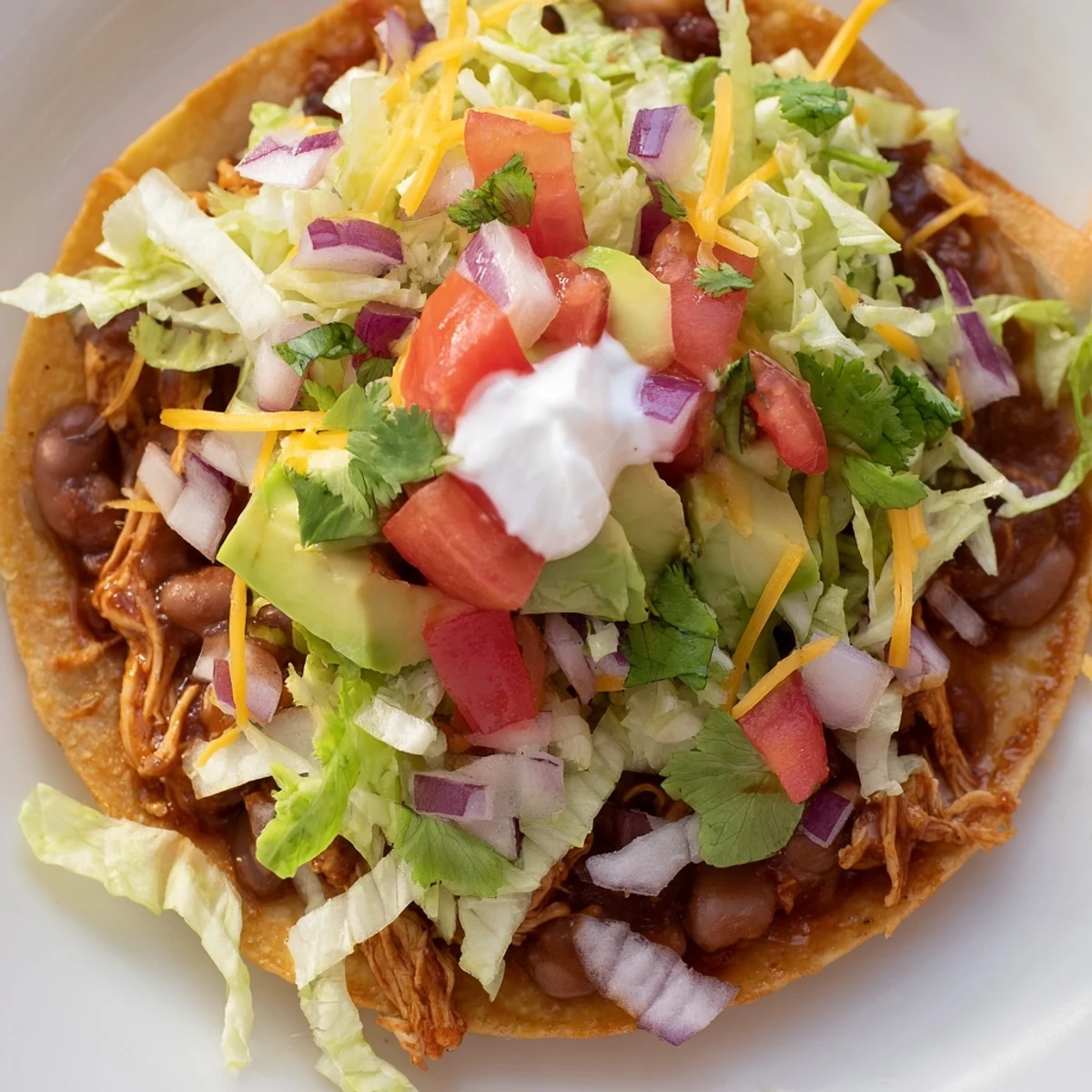 Crispy chicken tostadas loaded with fresh toppings and creamy cheese.