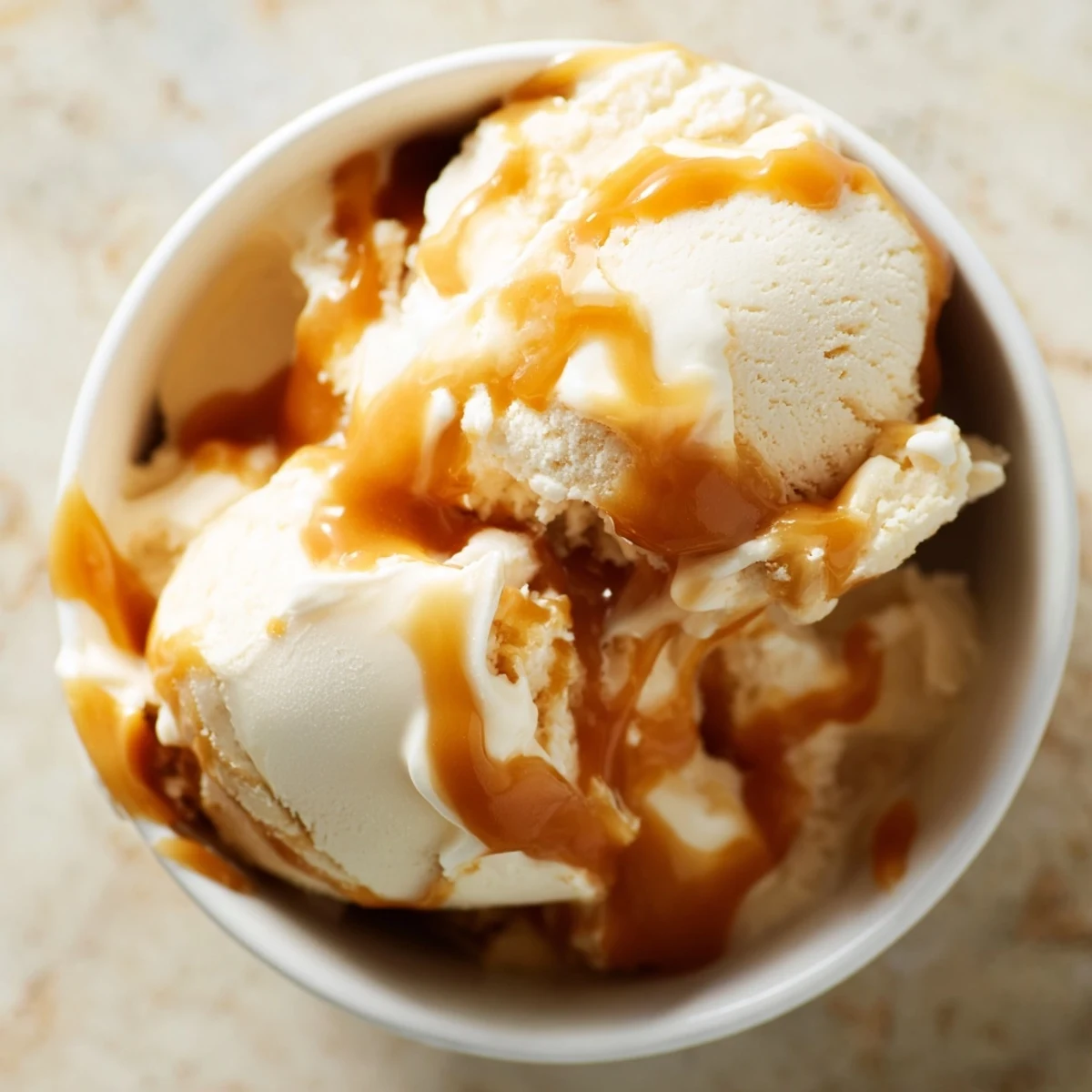Smooth halal salted caramel ice cream swirled with luscious caramel ribbons in a container.