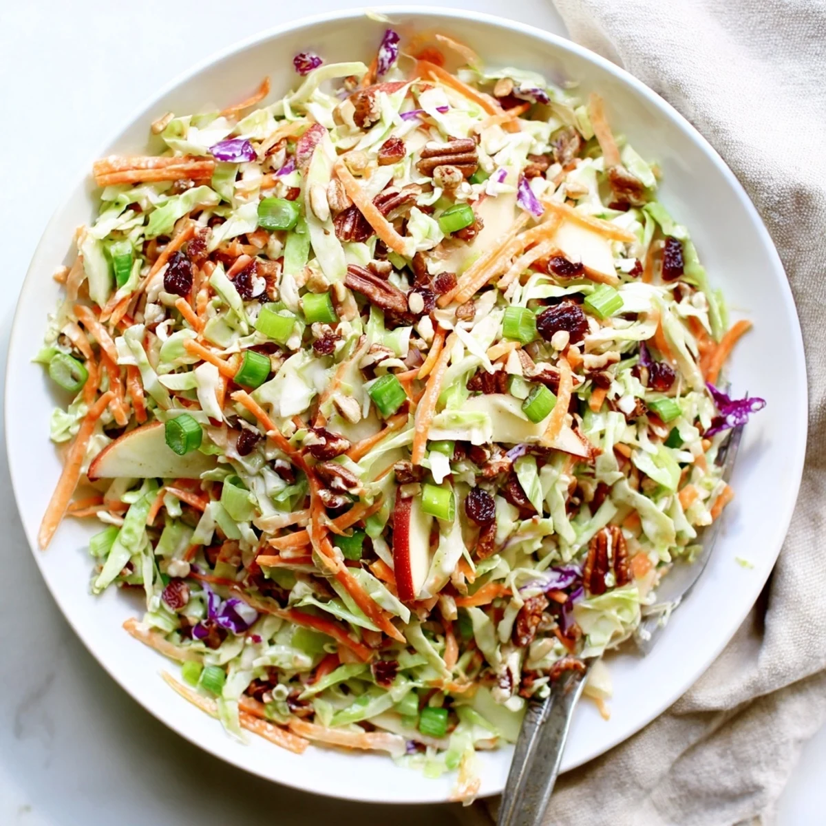 Vibrant bowl of cranberry apple coleslaw topped with crunchy chopped walnuts
