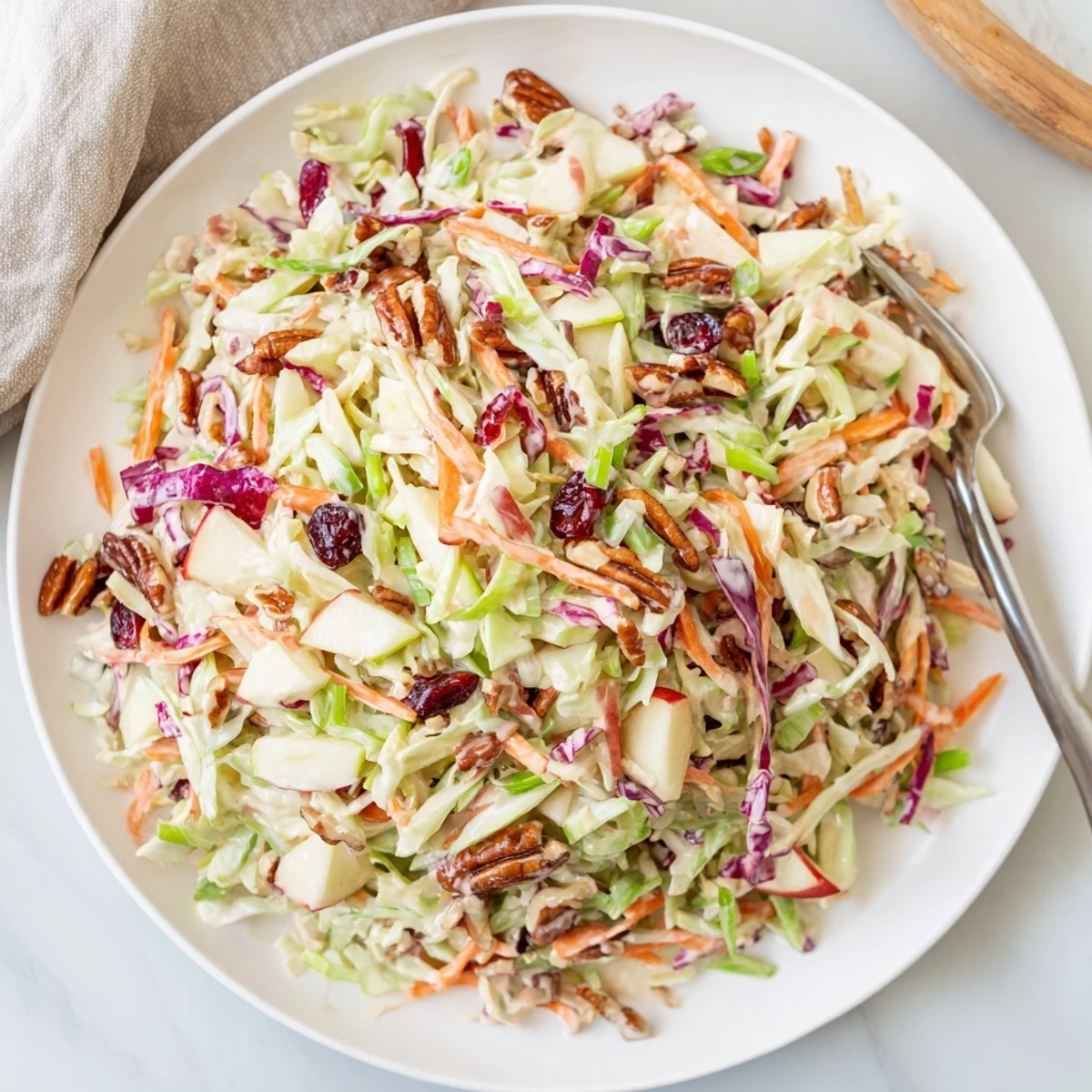Fresh cranberry apple coleslaw in a white bowl with green onion garnish