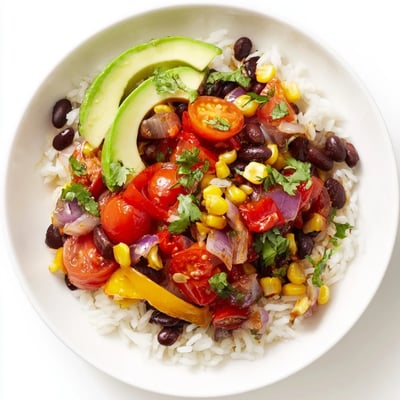 Hearty Cajun Spices Veggie Rice Bowl served in a rustic bowl with lime wedges and creamy avocado slices.  