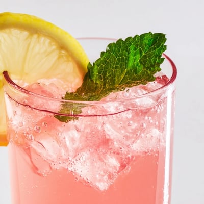 Refreshing honey lemon pink soda in a glass with ice and bubbles.  